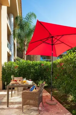 a red umbrella sitting next to a table and chairs at Résidence Marina Bianca in Santa-Lucia-di-Moriani