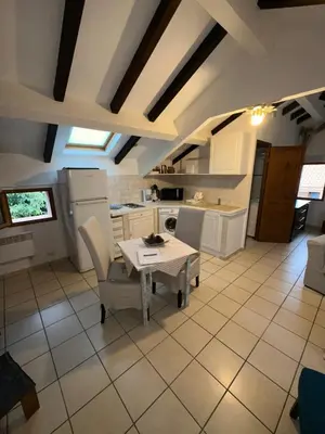 a kitchen with a table and chairs in a room at Studio Le Petit Nid d'Amour meublé Tourisme 3 étoiles Poggio in Santa-Lucia-di-Tallano