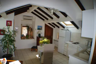 a kitchen with a table and a white refrigerator at Studio Le Petit Nid d'Amour meublé Tourisme 3 étoiles Poggio in Santa-Lucia-di-Tallano
