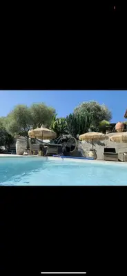 a swimming pool with two umbrellas and chairs at Residence Paradisu Ajaccio in Appietto