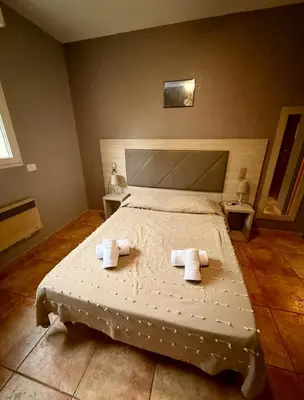 a bedroom with a bed with two towels on it at Hôtel - Pub Le Petit Bosquet in Santo-Pietro-di-Venaco