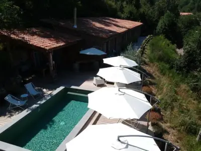 a swimming pool with white umbrellas and chairs and a swimming pool at Casa Santa Lucia in Bocognano