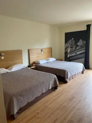 a hotel room with two beds and a painting on the wall at Logis Hotel Le Lonca in Porto Ota