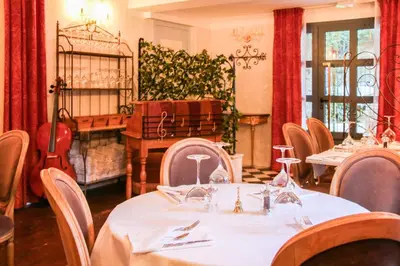 a dining room with tables and chairs and a room with a guitar at Hôtel Restaurant U Castellu Vizzavona in Vizzavona