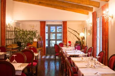 a restaurant with long tables and red chairs at Hôtel Restaurant U Castellu Vizzavona in Vizzavona