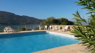 a swimming pool with chairs and a view of the water at Les Sables Blancs de la Liscia in Calcatoggio