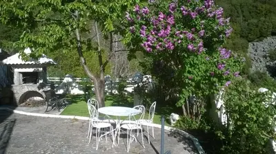 a table and chairs in a garden with purple flowers at Villa Emmony in Santo-Pietro-di-Venaco