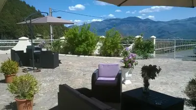a patio with a chair and flowers and an umbrella at Villa Emmony in Santo-Pietro-di-Venaco