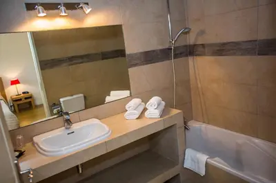 a bathroom with a sink and a mirror and a tub at Hotel Cesario in Calvi