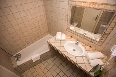 a bathroom with a sink and a tub and a mirror at Hotel Cesario in Calvi