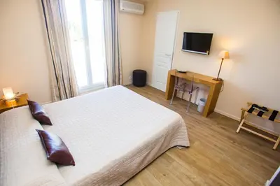 a bedroom with a white bed and a television at Hotel Cesario in Calvi