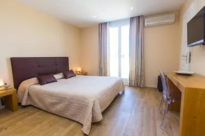 a bedroom with a bed and a desk and a television at Hotel Cesario in Calvi