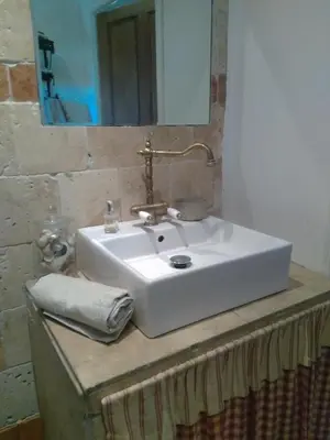 a white sink with a mirror on top of a counter at Maison de Campagne in Sarragia