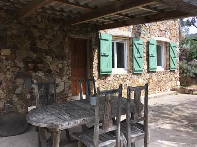 a wooden table and chairs in front of a stone house at Maison de Campagne in Sarragia