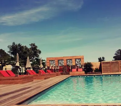 a swimming pool with red chairs and umbrellas at Isola Hôtel in Borgo
