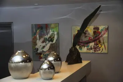 three silver vases sitting on a shelf with paintings at Isola Hôtel in Borgo