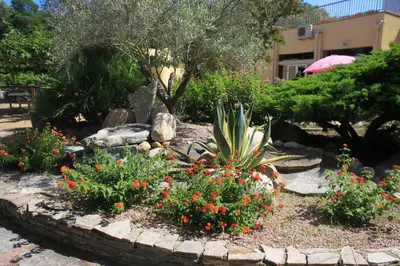 a garden with flowers and plants in front of a building at Isola Hôtel in Borgo