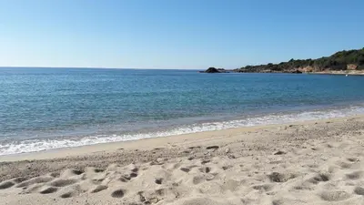 a beach with footprints in the sand next to the water at A U Mare in Sagone