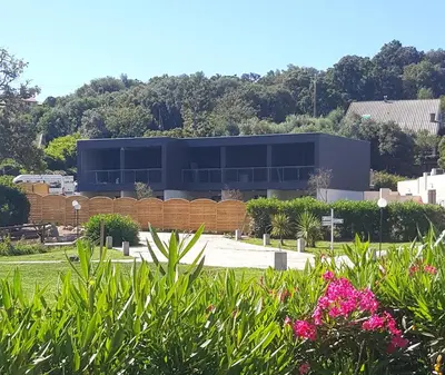 a building with a lot of windows in a park at Hotel Olmuccio in Sainte-Lucie de Porto-Vecchio