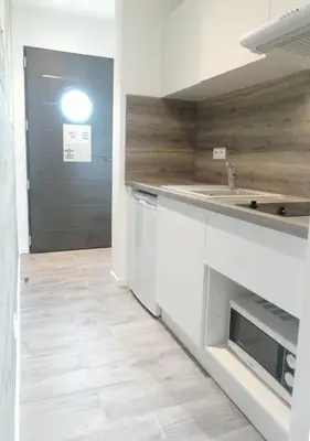 a kitchen with white cabinets and a sink and a door at Hotel Olmuccio in Sainte-Lucie de Porto-Vecchio
