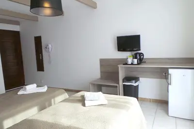 a room with two beds and a desk with a television at Hotel Olmuccio in Sainte-Lucie de Porto-Vecchio