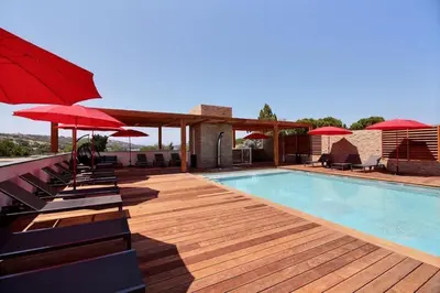 a swimming pool with chairs and umbrellas on a deck at Residence ACQUA LINDA Porticcio in Porticcio