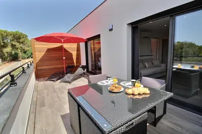 a balcony with a table and an umbrella at Residence ACQUA LINDA Porticcio in Porticcio