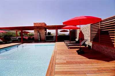 a pool with red umbrellas and chairs and a swimming pool at Residence ACQUA LINDA Porticcio in Porticcio