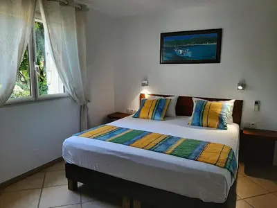 a bedroom with a large bed with two windows at Villa Cartarana in Bonifacio