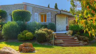 a stone house with stairs in front of a yard at Villa Cartarana in Bonifacio