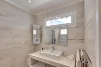 a white bathroom with a sink and a window at Les Appartements du Port in Bonifacio