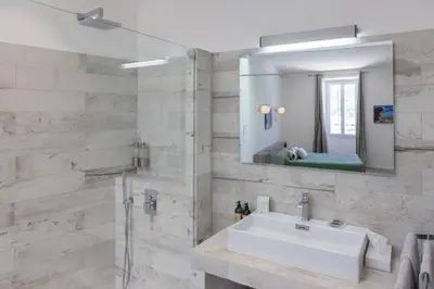 a bathroom with a sink and a mirror at Les Appartements du Port in Bonifacio