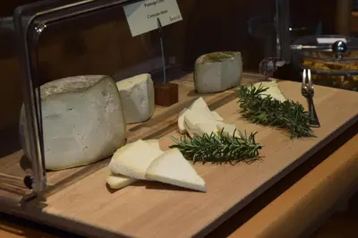 a wooden cutting board with cheese on a table at Hotel Spa Genovese in Bonifacio