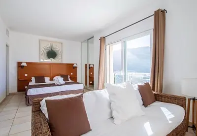 a hotel room with a couch and a bed at Hôtel Lilium Maris in Sartène