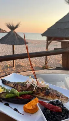 a plate of food on a table at the beach at Hôtel Lilium Maris in Sartène