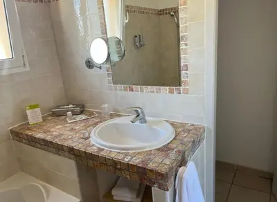 a bathroom with a sink and a mirror at Hôtel Lilium Maris in Sartène