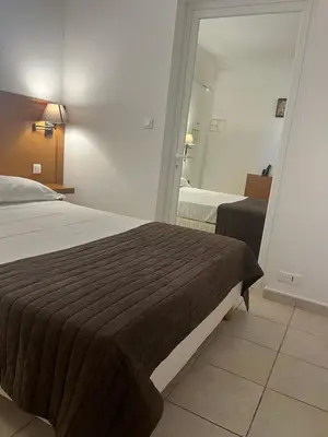 a hotel room with a bed and a mirror at Hôtel Lilium Maris in Sartène