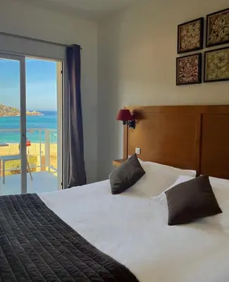 a bedroom with a bed with a view of the ocean at Hôtel Lilium Maris in Sartène