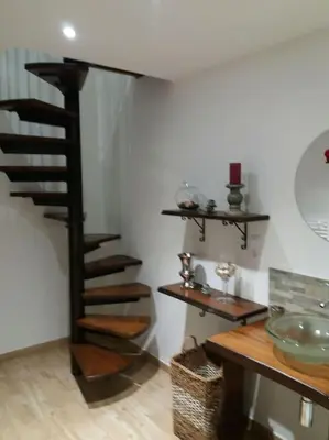 a black spiral staircase in a room with a table at Domaine Colonna-Santini Gîte avec Piscine & Spa, Vue Mer et Montagnes in Porri