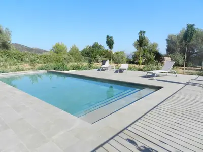 a swimming pool with two chairs and a patio at Cantari in Calenzana