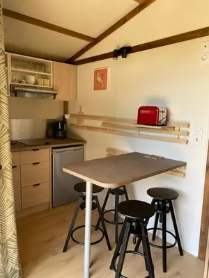 a small kitchen with a table and four stools at Ri-Veu corse dans camping marina di sorbo in Sorbo-Ocagnano