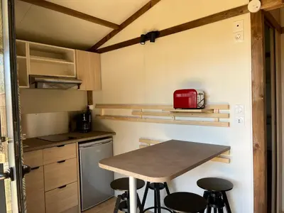 a small kitchen with a table and some stools at Ri-Veu corse dans camping marina di sorbo in Sorbo-Ocagnano