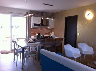 a kitchen with a wooden table and a blue chair at L'Hacienda Piscine chauffée à 28, spa, boulodrome et court de Tennis privés, 2 villas indépendantes in Porto-Vecchio