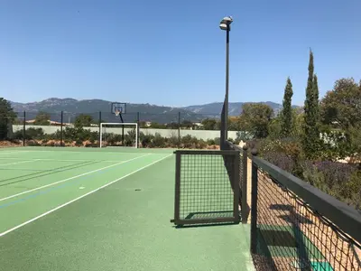 a green tennis court with a net on it at L'Hacienda Piscine chauffée à 28, spa, boulodrome et court de Tennis privés, 2 villas indépendantes in Porto-Vecchio