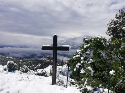 a cross on top of a snow covered mountain at Parfumu Di Celu in Corte