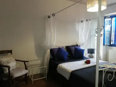 a bedroom with a bed with blue pillows and a chair at Parfumu Di Celu in Corte