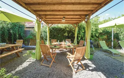 a patio with a wooden pergola with a table and chairs at 3 Bedroom Gorgeous Home In Cervione in Cervione