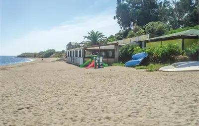 a sandy beach with a house and a playground at 3 Bedroom Gorgeous Home In Cervione in Cervione