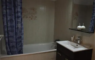 a bathroom with a sink and a tub with a shower curtain at 3 Bedroom Lovely Home In Cervione in Cervione