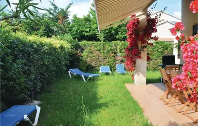 a yard with two blue chairs and flowers at 3 Bedroom Lovely Home In Cervione in Cervione